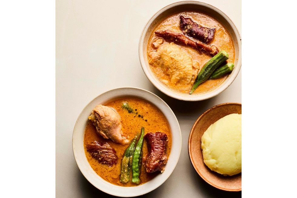 Deux bols de soupe aux arateurs ouest-africains avec de la viande, du gombo et des légumes servis aux côtés d'igname ou de fufu blanc moulté.