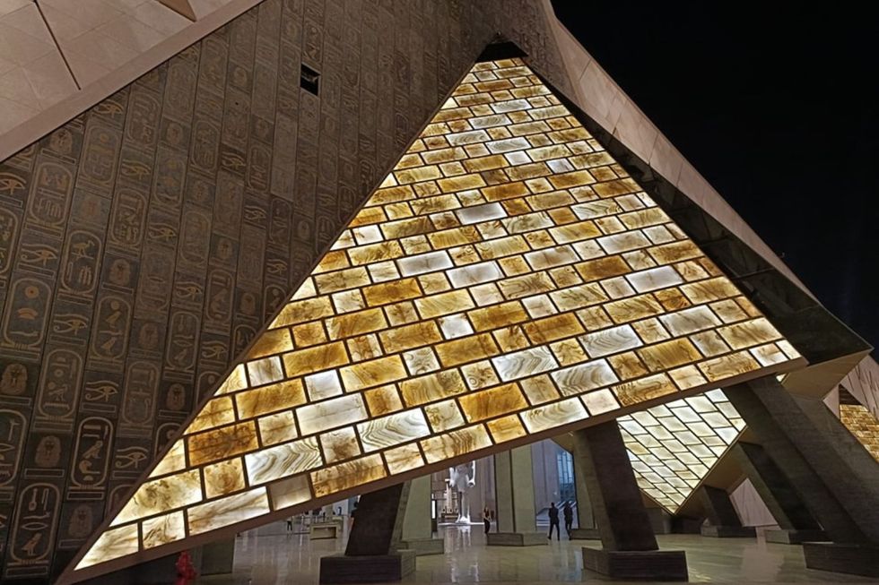 L'entrée en forme de pyramide du Grand Egyptian Museum, en pierres noires avec des hiéroglyphes et des pierres de couleur ambre.