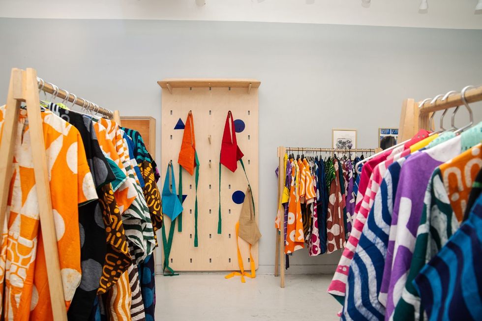 Un couloir avec des cintres en bois remplis de vêtements aux couleurs vives.
