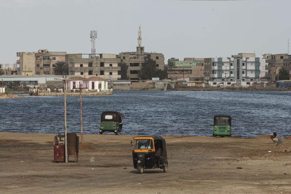 Une vue sur le port de la ville avec des tuk-tuks et des bâtiments de l'autre côté de la rivière