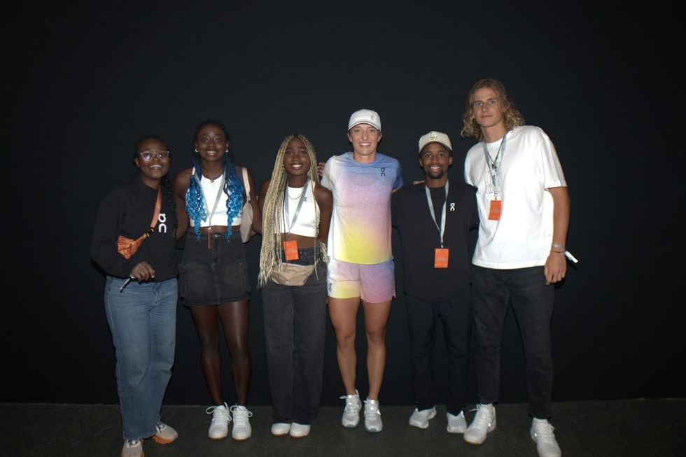 Six personnes debout côte à côte sur un fond noir, tous souriants et portant des longes d'événements.