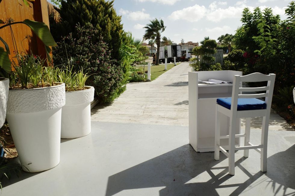 Une chaise haute blanche et un piédestal à l'entrée d'un restaurant, où il faudrait montrer un code QR pour entrer.