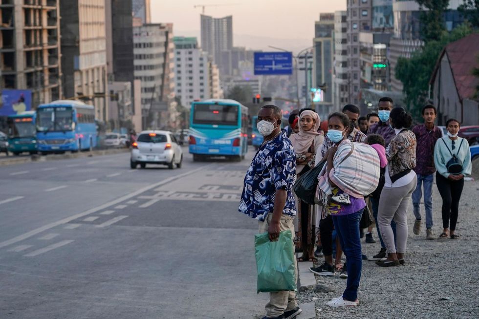 Les navetteurs portant des masques en ligne avec les protocoles de coronavirus font la queue pour les transports publics à Piassa pendant les heures de pointe le 25 décembre 202, à Addis-Abeba, en Éthiopie.