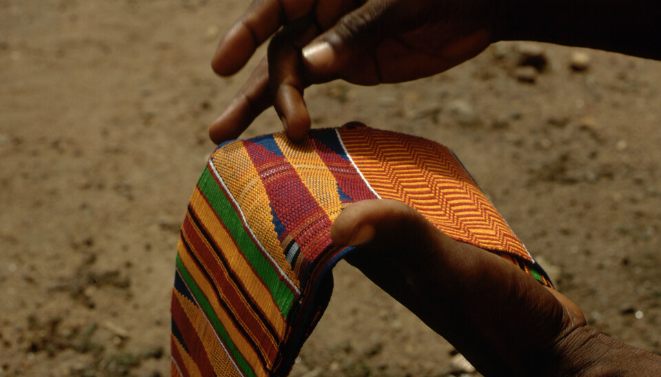 Le tissu Kente est un tissu traditionnel Ashanti tissé par les hommes. Lieu : Bonwire, Ghana. Un homme tenant un morceau de tissu Kente.