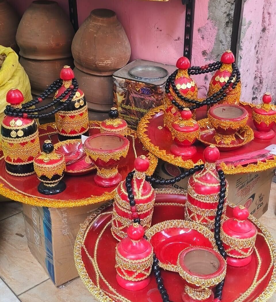 Trois plateaux rouges portant des tasses et des bols rouges de formes différentes ornés d'or, ainsi que des chapelets en bois noir.