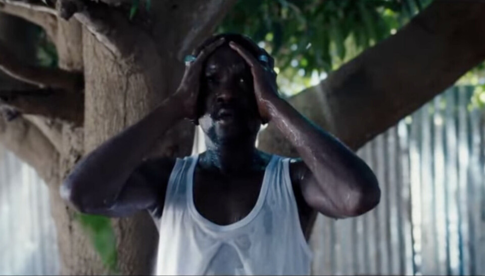 On voit un homme en maillot blanc se couvrant le visage avec ses paumes.