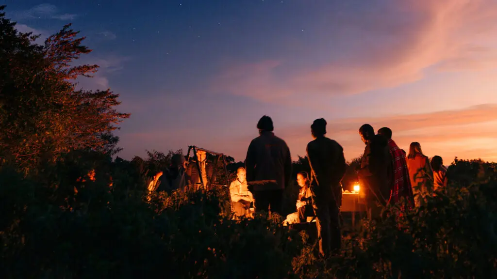 un groupe d'invités d'Embo ensemble autour du feu de camp à Emboo dans le Masai Mara