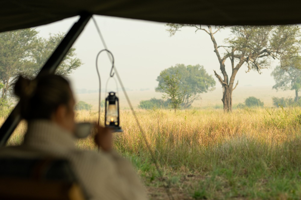 Un invité savoure un café le matin avec vue sur les plaines du Serengeti, en Tanzanie