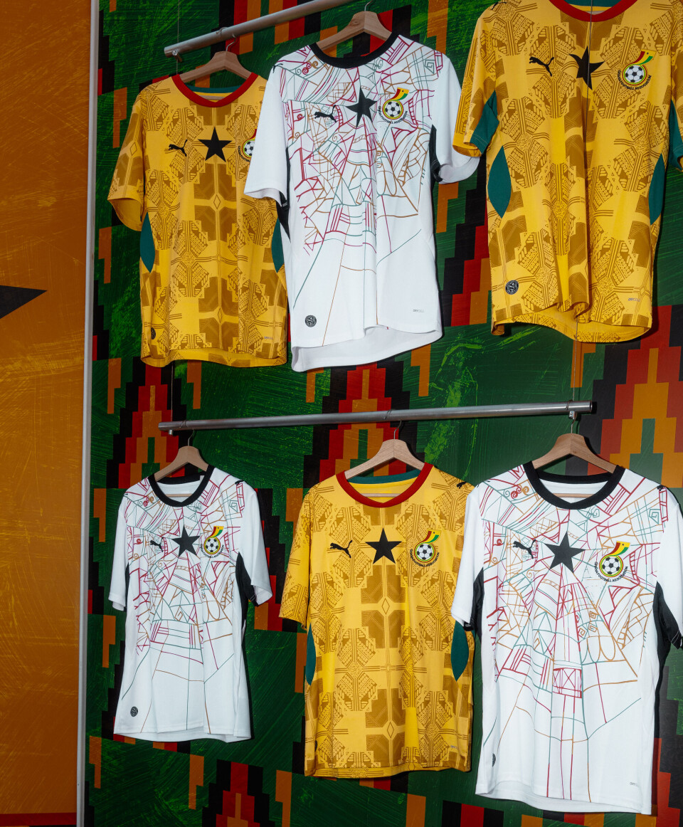 Trois maillots de football sur cintres, deux jaunes avec une étoile noire au milieu et un blanc avec une étoile noire au milieu.