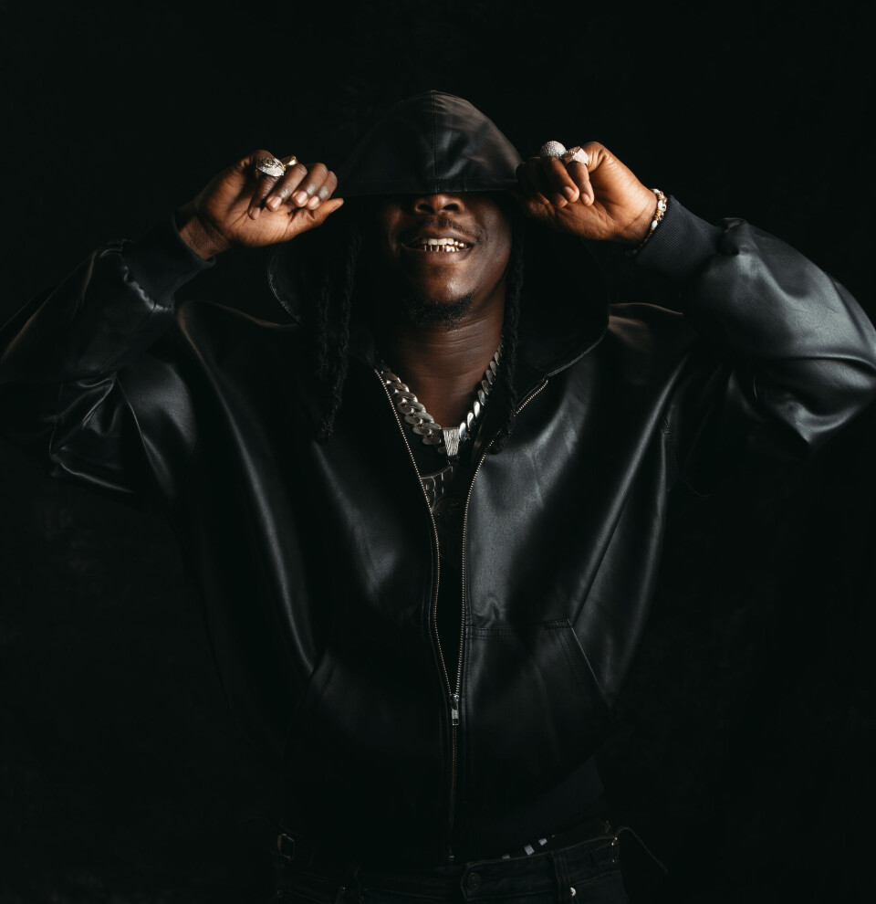 Une image de Stonebwoy portant une veste en cuir noire.