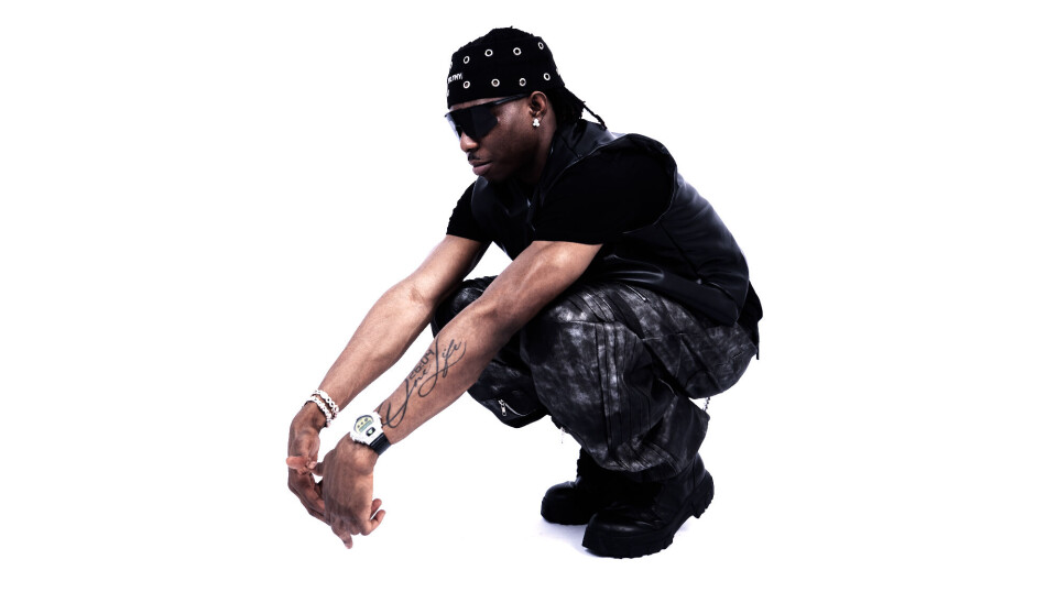 Une photographie de la chanteuse FOLA accroupie derrière un fond blanc.