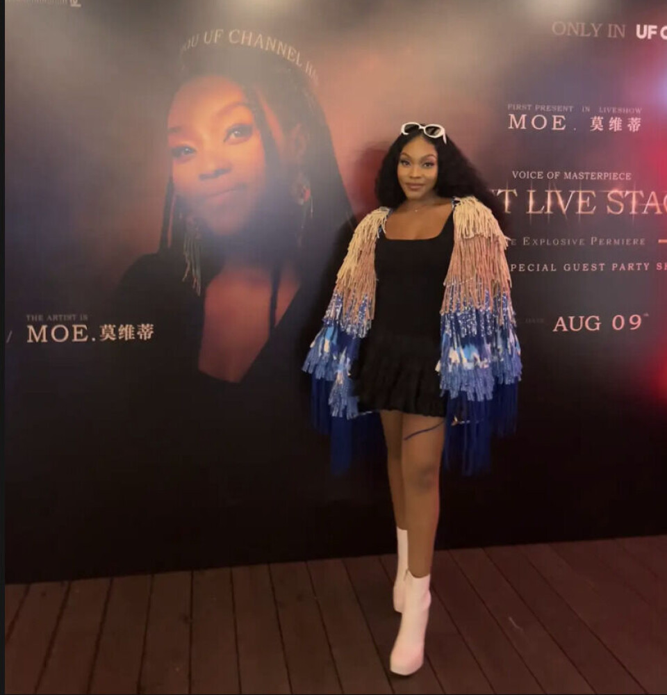Moe se tient devant une affiche d'elle-même.