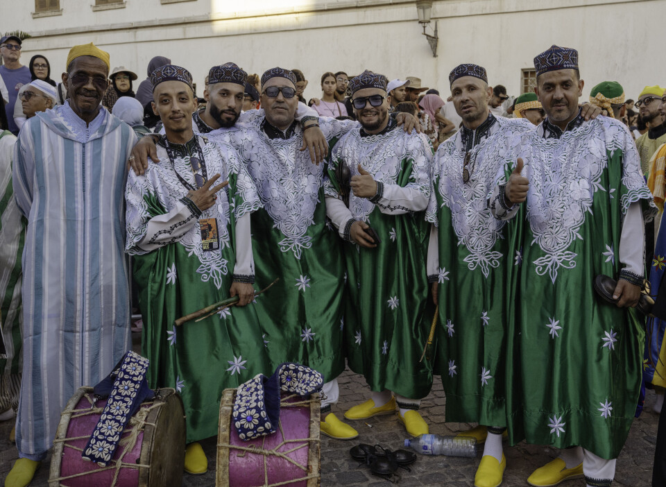 Sept hommes posent pour la caméra ; six d’entre eux portent des vêtements traditionnels marocains verts.