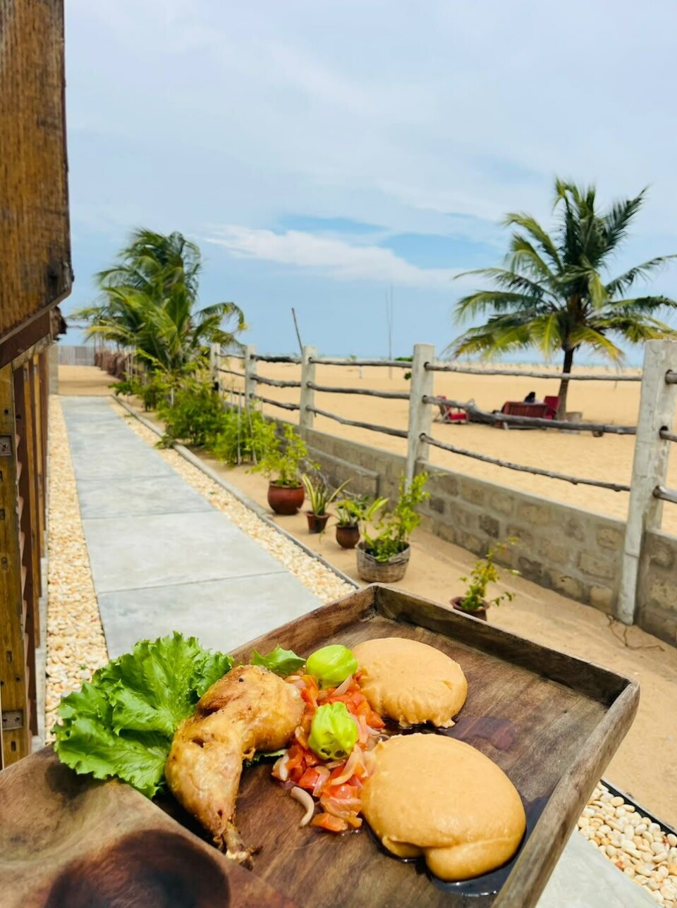Burgers et fritures sur une planche de bois donnant sur une plage tropicale.