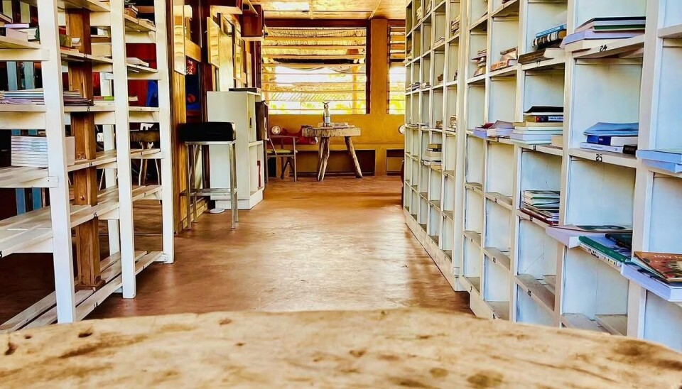 Observez une allée d'archives en bois avec des étagères et des tables blanches au loin.