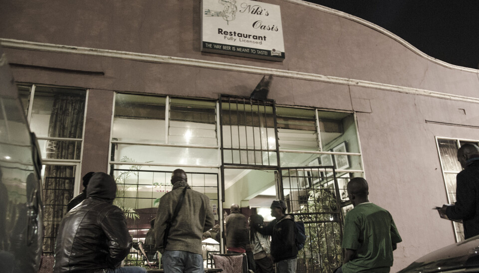 Les gens se tiennent devant l'oasis de Niki à Newtown la nuit.
